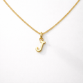 Gold necklace with a 'J' pendant on a white background