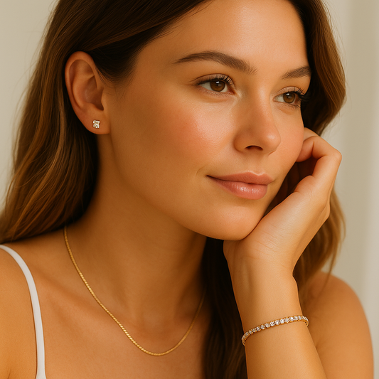 Woman wearing gold necklace, earrings, and bracelet against a neutral background
