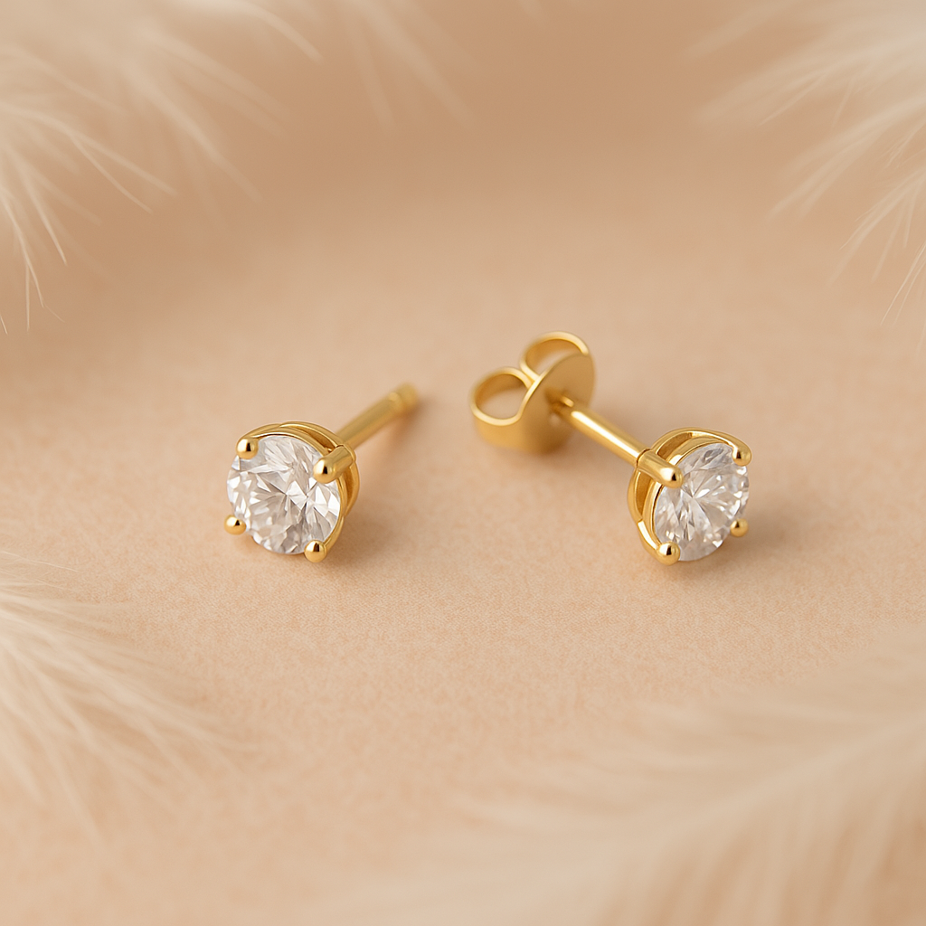 Gold stud earrings with clear gemstones on a beige fur background