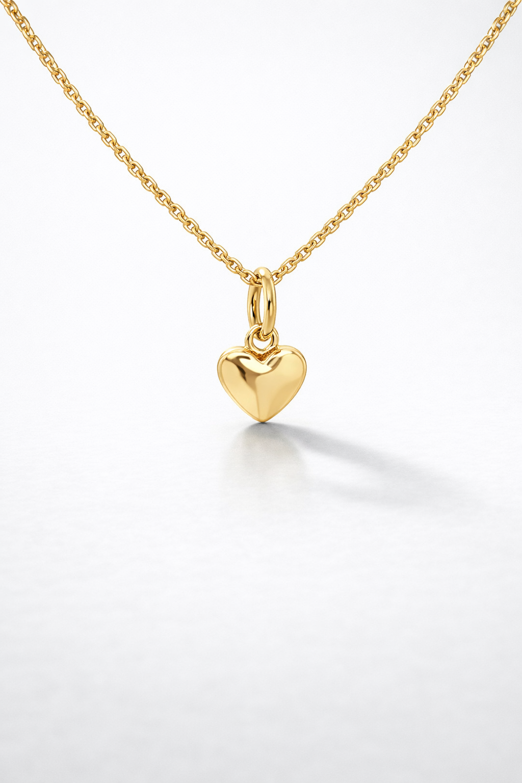 Gold heart-shaped pendant on a gold chain against a white background