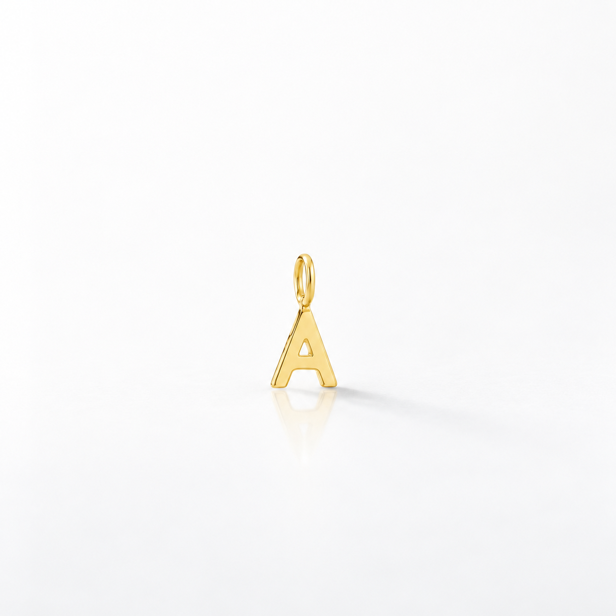A polished gold initial letter 'A' charm pendant with a top loop, shown on a clean white reflective surface.