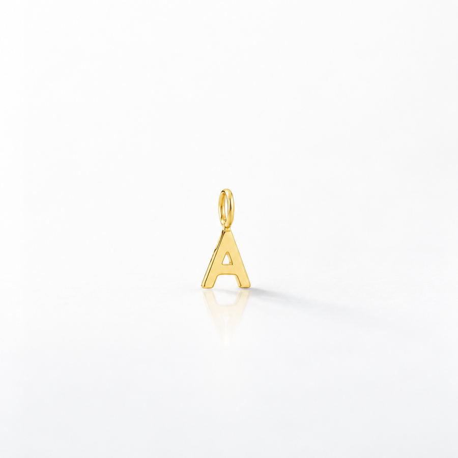 A polished gold initial letter 'A' charm pendant with a top loop, shown on a clean white reflective surface.