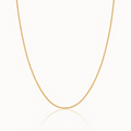 A delicate yellow gold chain necklace displayed in a U-shape against a clean white background with a subtle reflection below.