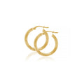 Pair of polished 9ct yellow gold 15mm tube hoop earrings, shown overlapping with hinged closures and a soft reflection on a white background
